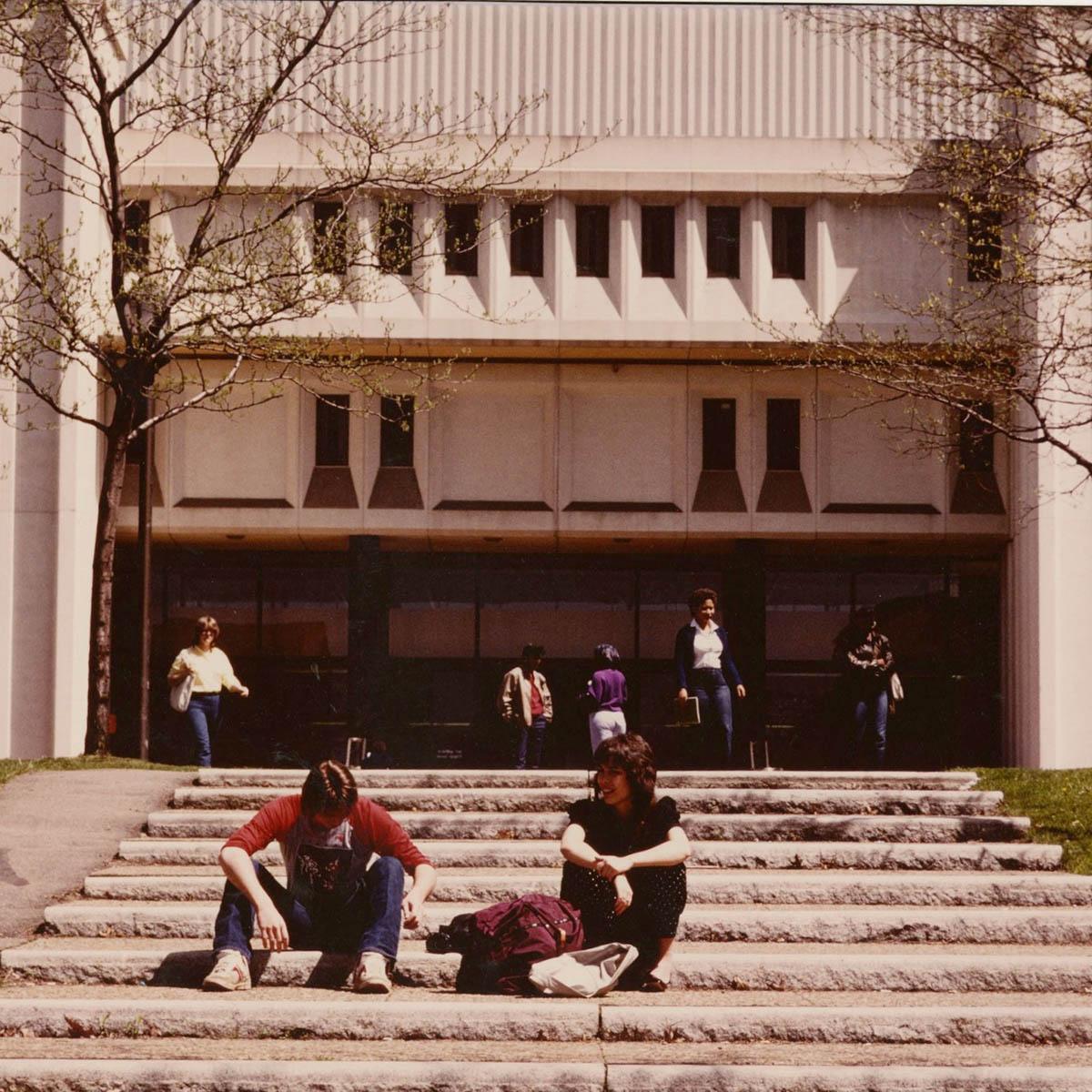 Vintage photograph from Chatham University archives of 学生s circa 1970s seated on the steps of JKM Library