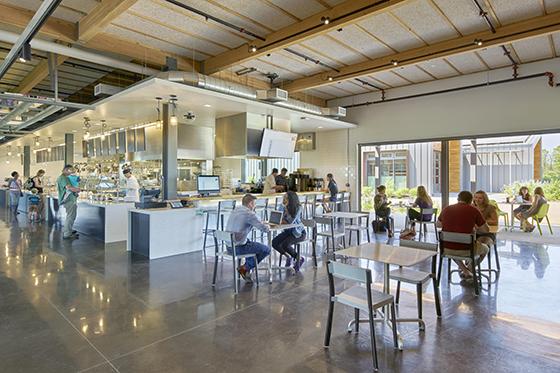 Photo of Chatham University's Eden Hall Commons cafeteria, a large industrial space with natural light filled with people at tables